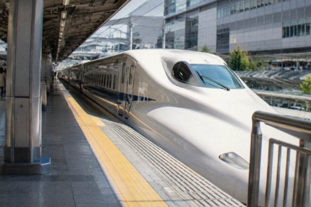 A sleek Japanese bullet train waiting at a station platform beside a modern station hall