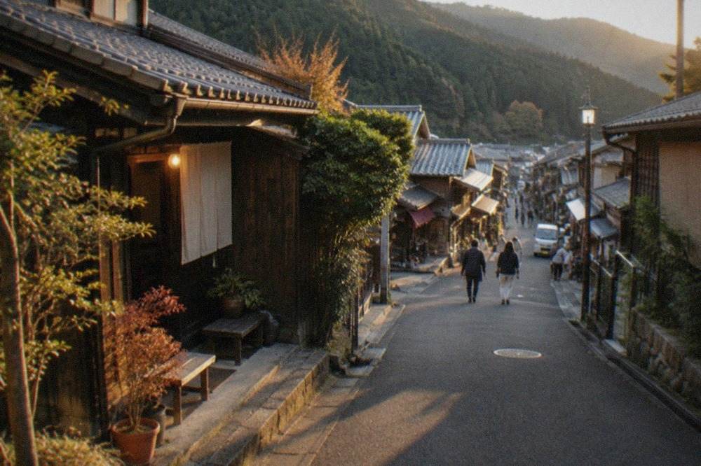 A quiet mountain village street in northern Kyoto with traditional wooden buildings and forested slopes behind