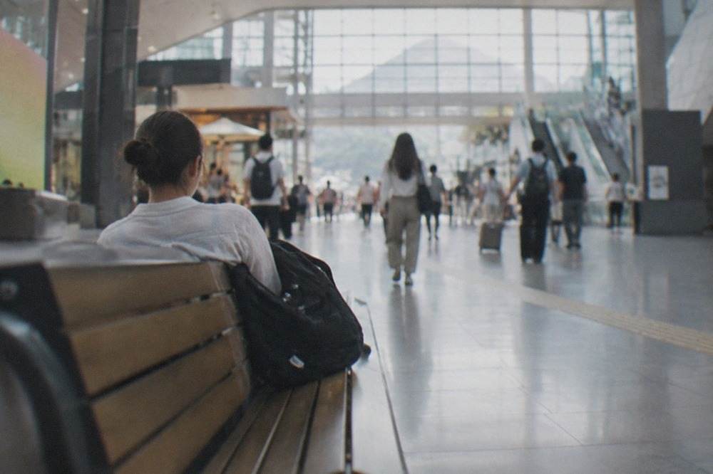 A traveller resting on a bench in a bright modern train station concourse