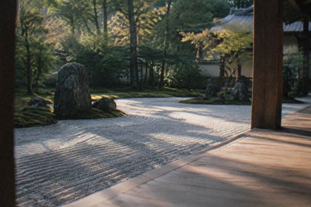 A raked gravel Zen rock garden at a Kyoto temple viewed from a wooden veranda in soft morning light