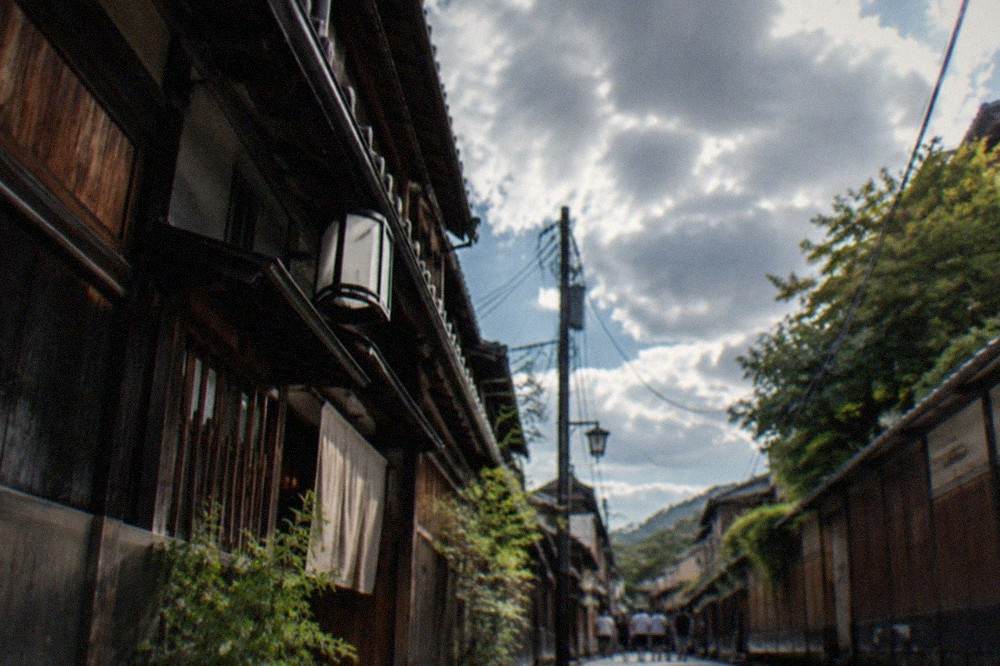 A wooden sign in Japanese and English at the entrance of a Gion alley, warning against photography and unauthorized entry on the private lane