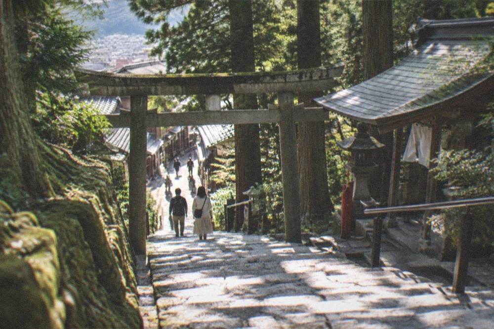 A forested mountain trail north of Kyoto with cedar trees, stone steps and a small shrine gate