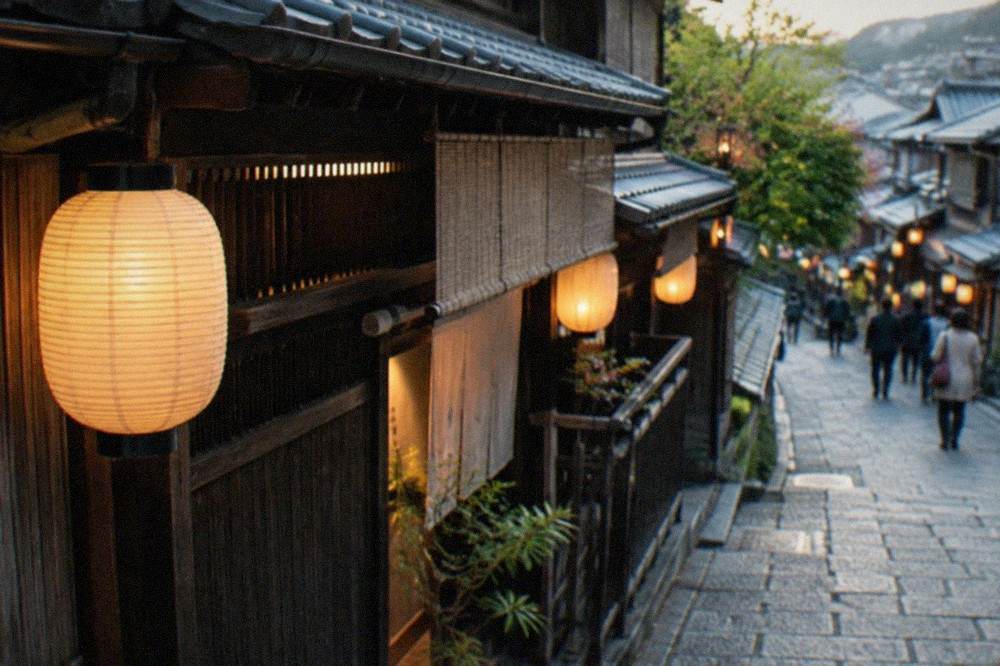 Lanterns hanging outside wooden teahouses on a Gion lane in the evening