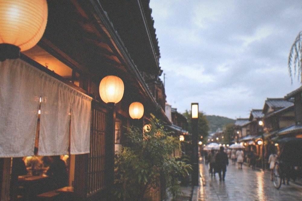 A small izakaya restaurant with paper lanterns and noren curtains in Gion at night