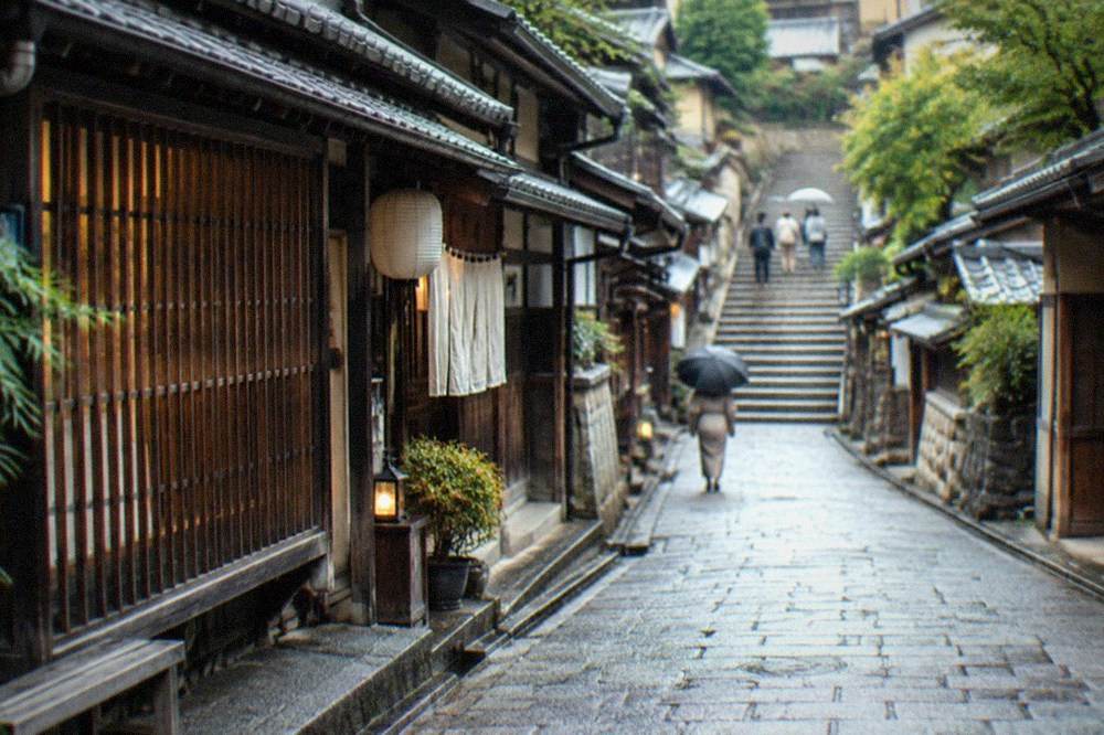 Narrow stone-paved slope street in Kyoto with traditional lattice-fronted shops and a stone staircase ahead