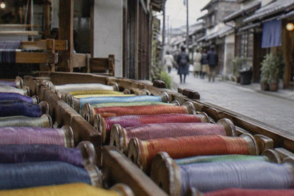 Rows of dyed silk threads wound on wooden bobbins in a weaving workshop