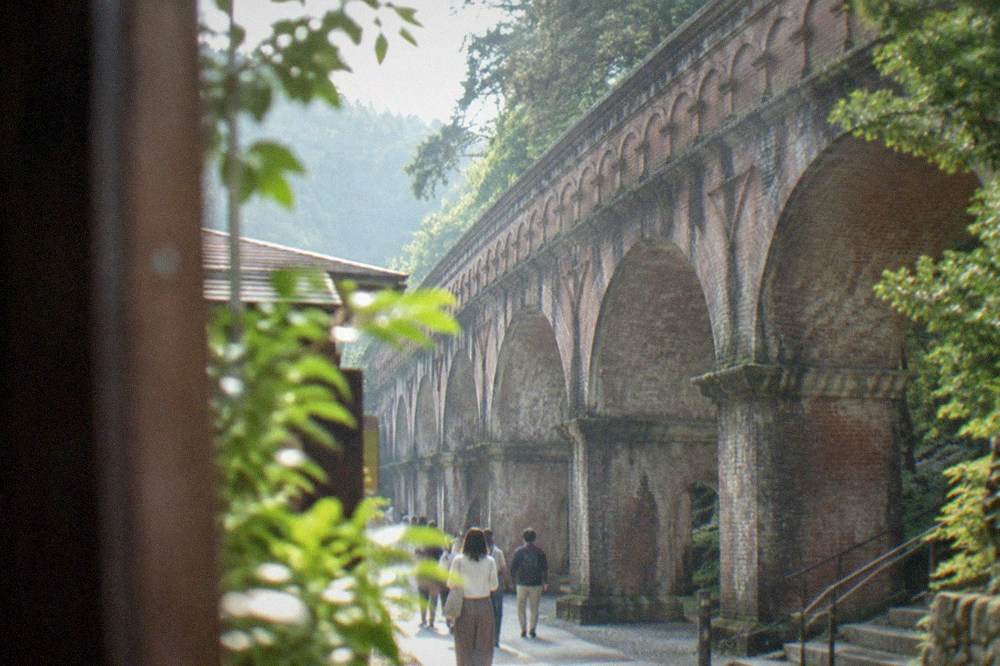 The red brick Lake Biwa Canal aqueduct arches crossing a wooded slope beside Nanzen-ji temple