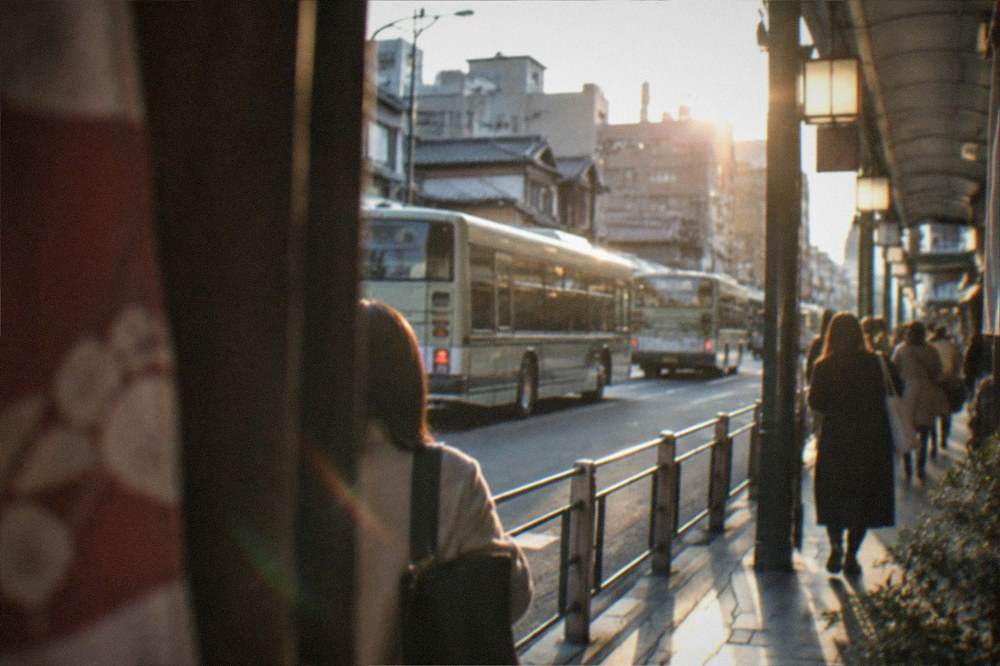 Buses and pedestrians on Kawaramachi-dori beside a covered arcade entrance