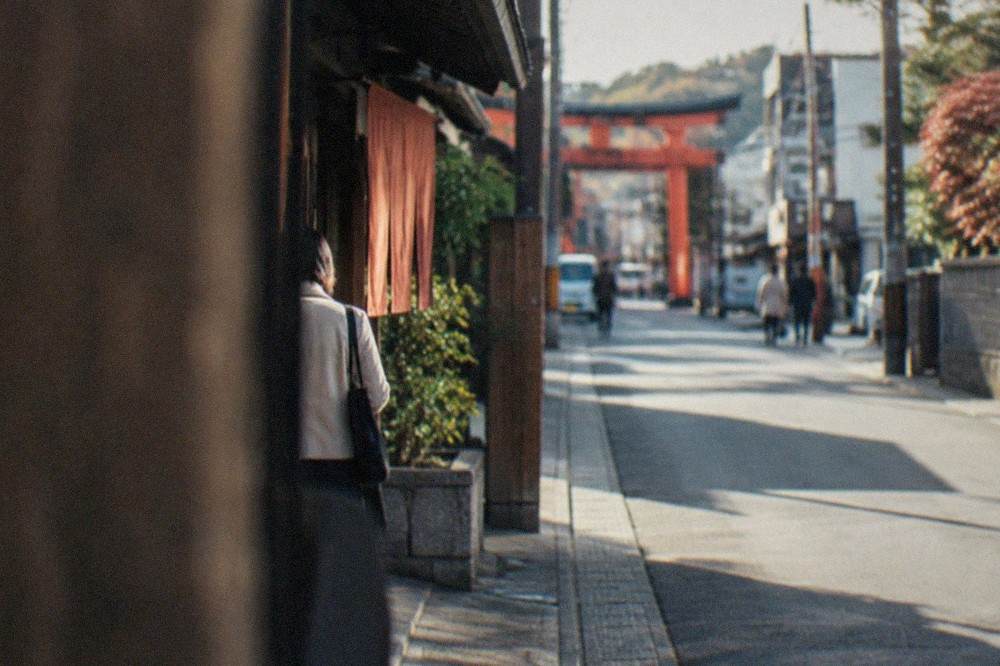 Wooden sake barrels stacked outside a brewery entrance in Fushimi