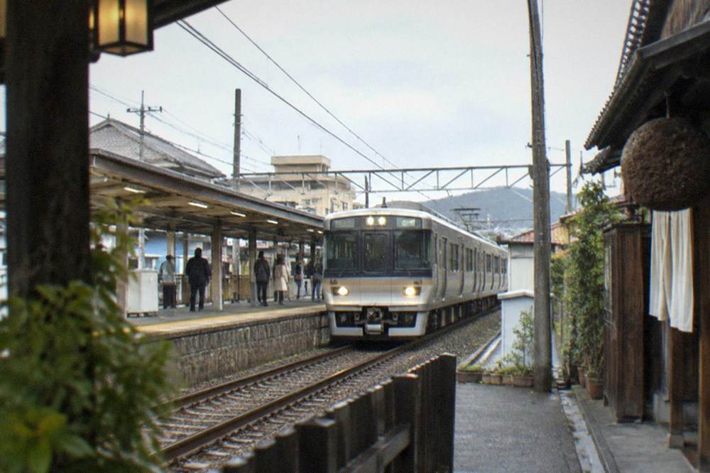 A train pulling into a small suburban station near the Fushimi brewing district