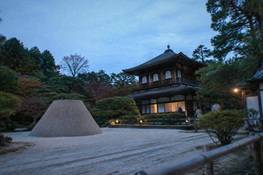 A wide raked gravel platform and a tall sand cone in a temple garden