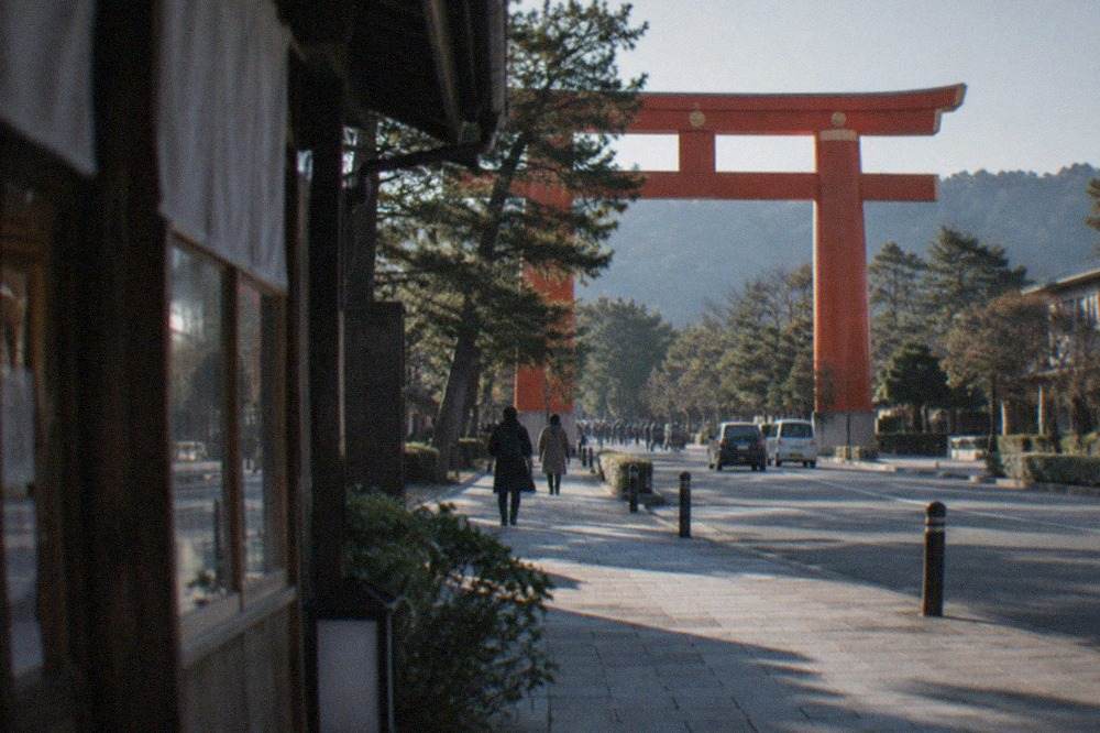 The large red torii gate of Heian Shrine rising above trees in Kyoto