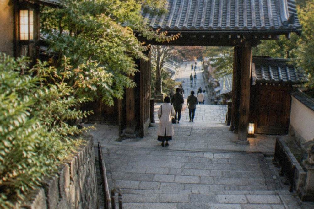 A Zen temple gate and stone path lit softly in the evening in Kyoto's Higashiyama district