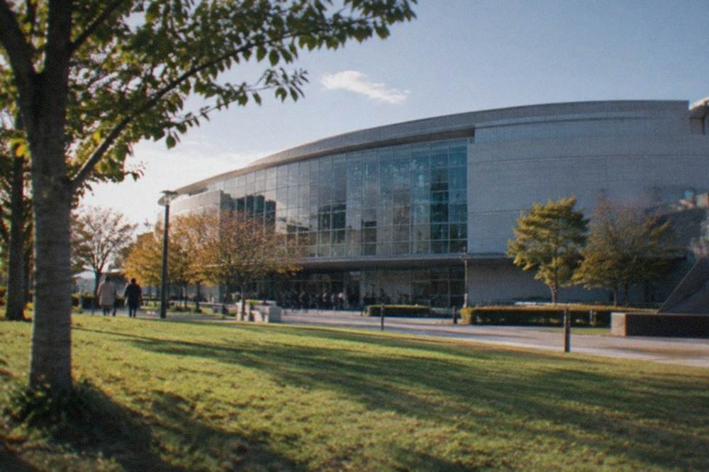 A large modern aquarium building seen from a park lawn on a clear day