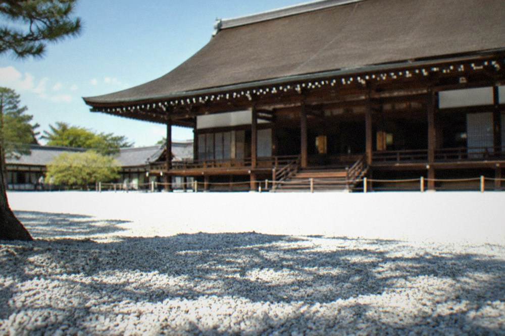 A traditional Japanese ceremonial hall with a cypress bark roof and wooden columns standing above a wide white gravel courtyard
