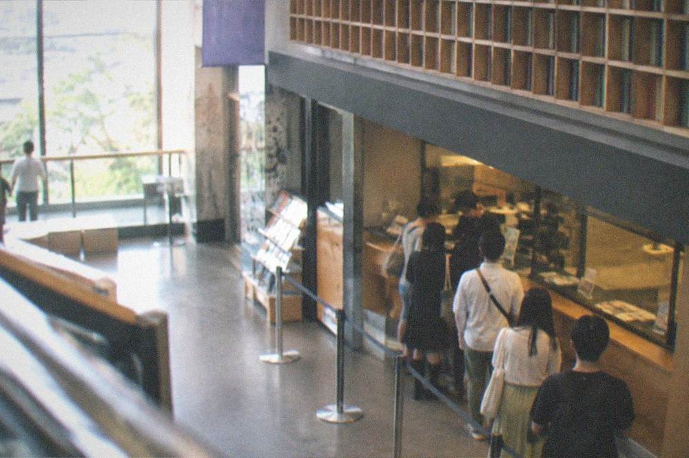 A museum ticket counter with a small queue of visitors