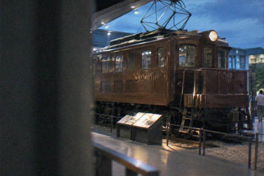 A vintage electric locomotive displayed under bright museum lighting with information panels beside it
