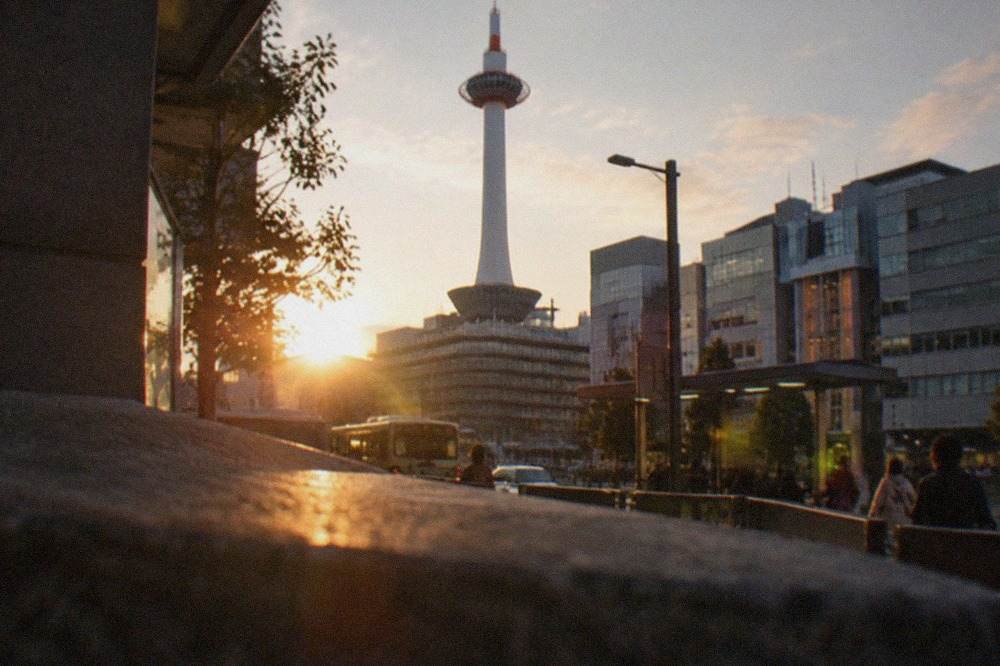 The white Kyoto Tower shaft rising above the station district at dusk