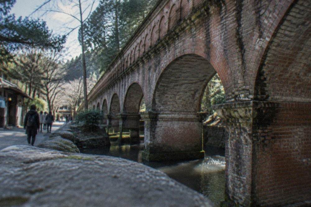 A brick arched aqueduct carrying a canal through green woodland at Nanzen-ji
