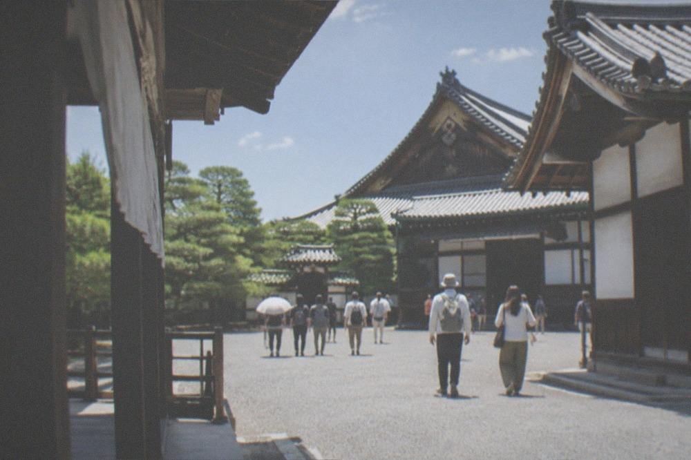 Visitors walking a gravel path between palace buildings at Nijo Castle
