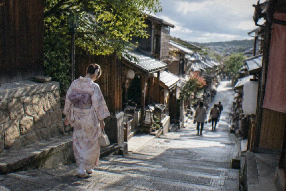 A woman in a rented kimono walking carefully down the stone steps of Sannenzaka