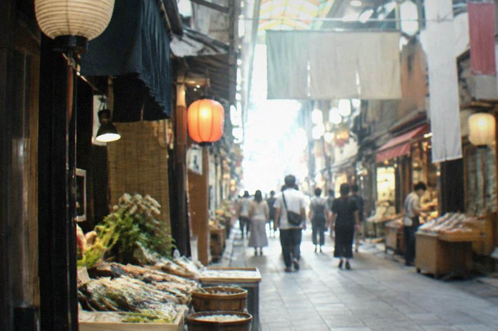 A narrow covered shopping lane with lanterns and small shopfronts under a ceiling