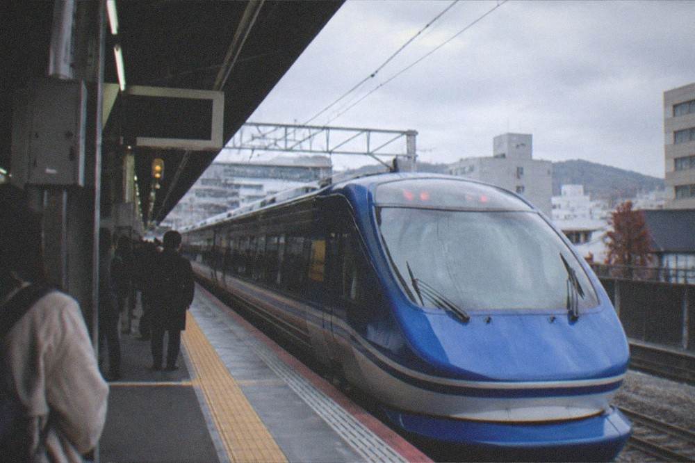 The platform of Kyoto Station with a blue limited express train waiting beside departure boards