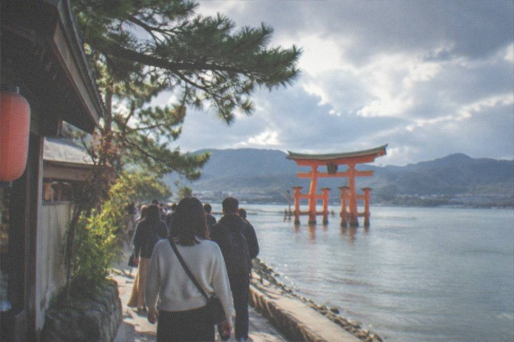 Visitors walking along the waterfront path toward Itsukushima Shrine on Miyajima