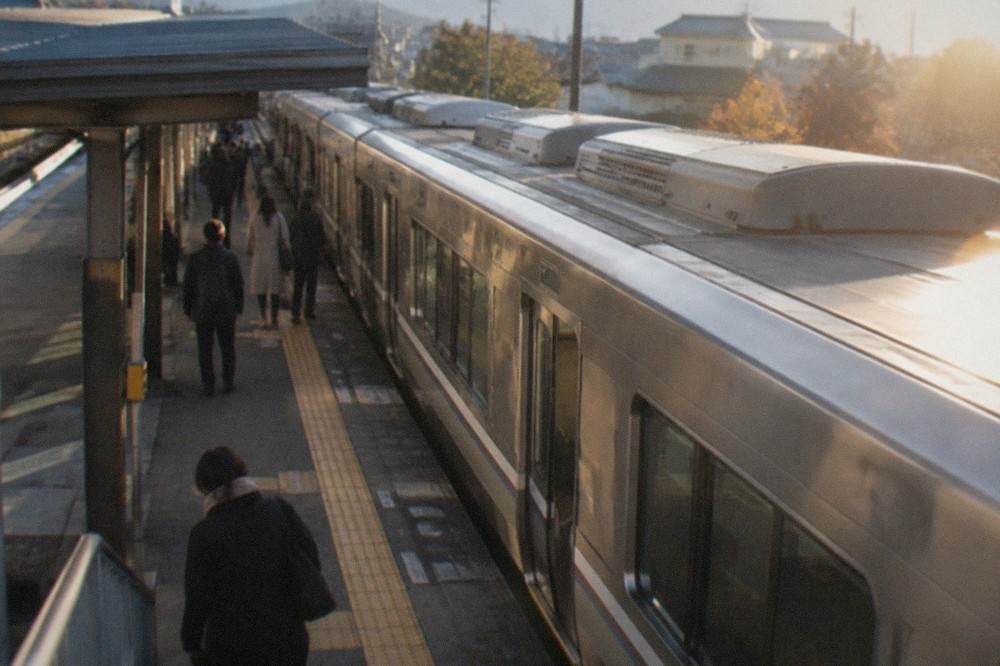 A silver rapid train waiting at a platform beside a station sign