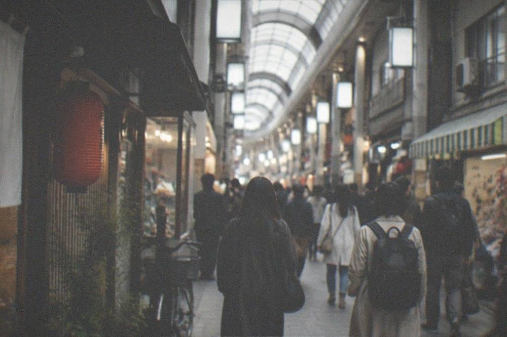 Commuters walking through a busy covered shopping arcade in Osaka in the early evening