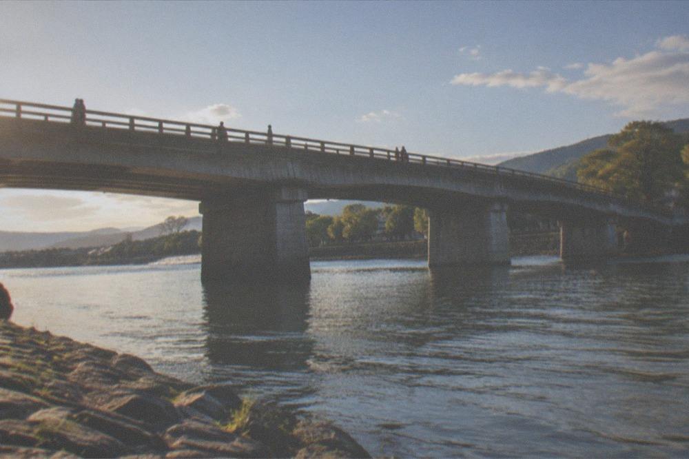 A stone bridge over the wide Uji River with tree-lined banks