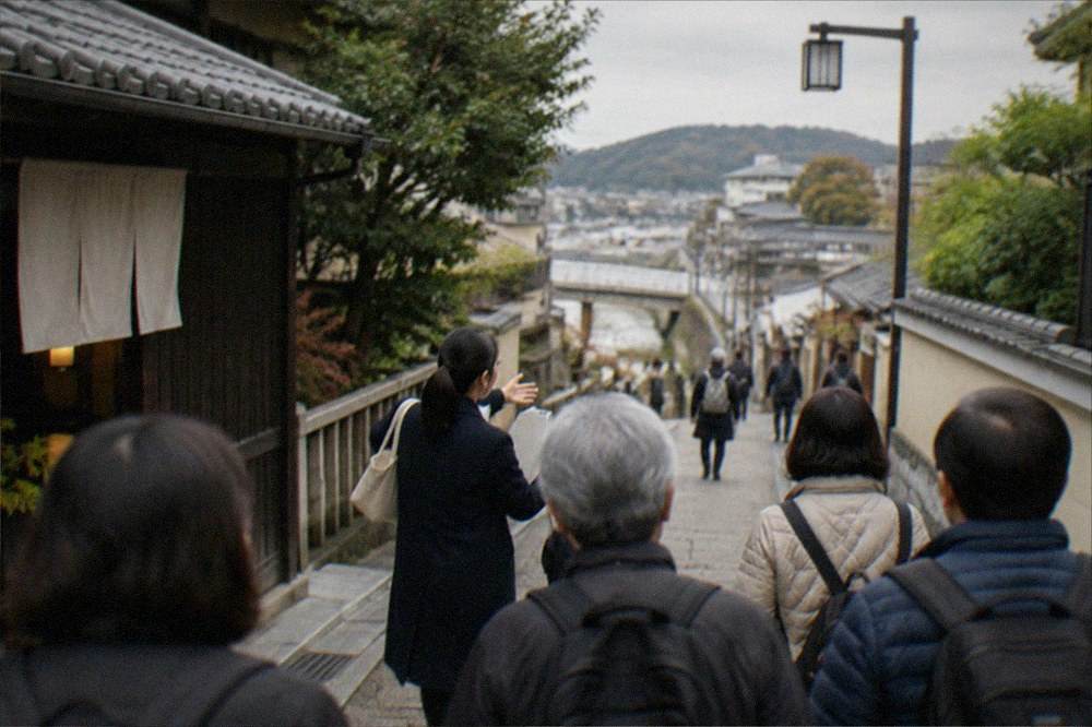 A guide leading a small group of visitors along a street in Uji