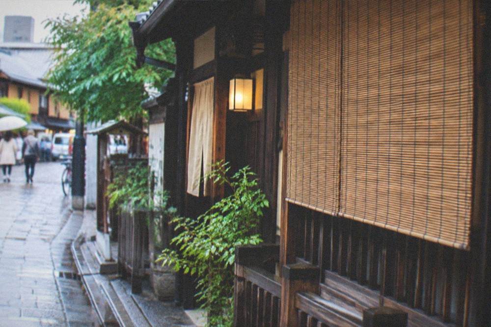 A traditional wooden machiya townhouse facade with bamboo screens in Kyoto