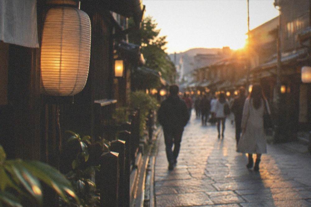 A covered shopping arcade of food stalls with hanging lanterns and shoppers in Nishiki Market