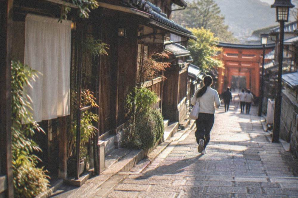 A quiet stone-paved lane with traditional wooden buildings in eastern Kyoto at dusk