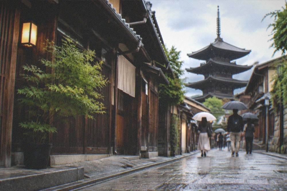 Visitors walking along a traditional wooden machiya street in eastern Kyoto