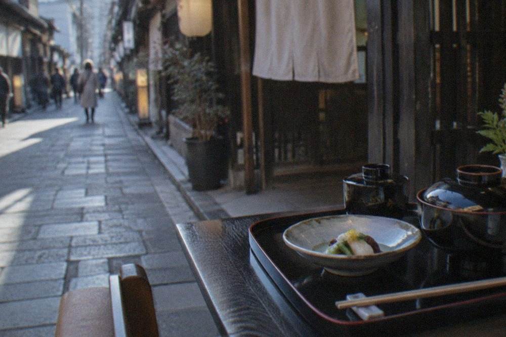 A formal Japanese dinner table set with lacquerware bowls and a small arranged dish