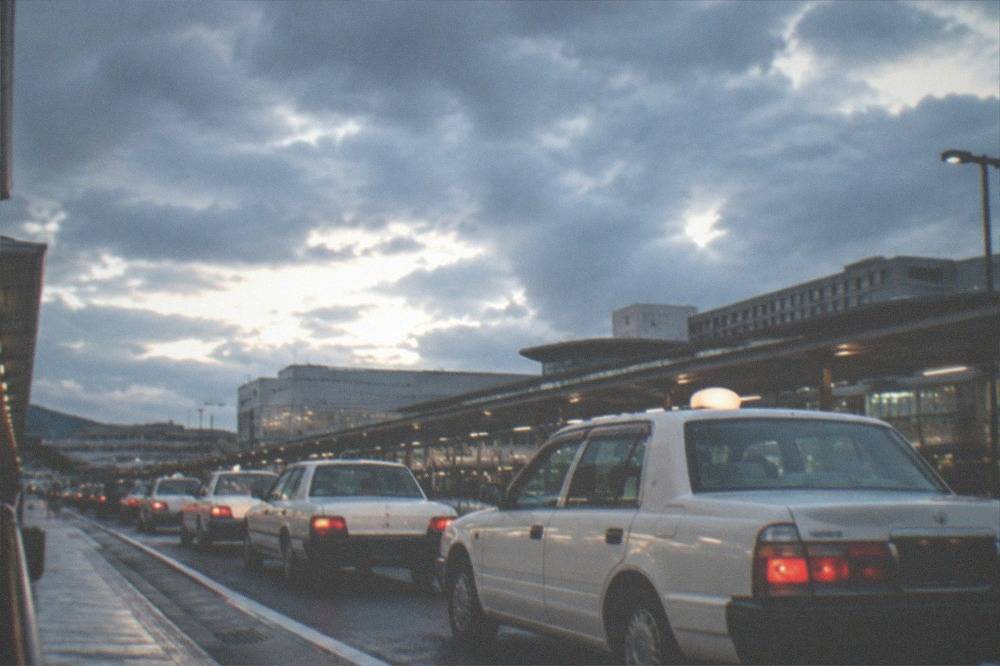 A row of white taxis waiting at a night-time airport rank