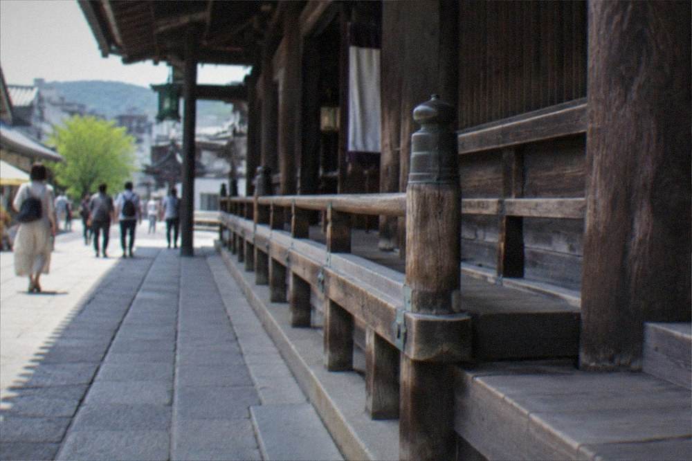 A long wooden temple hall exterior with a level stone walkway alongside