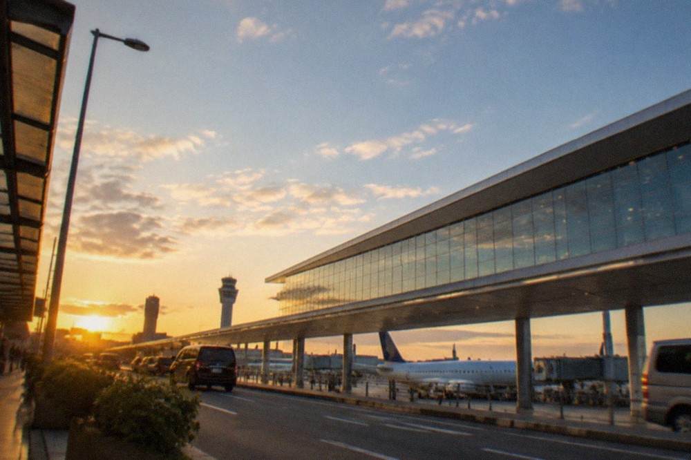 An airport terminal building with airliners parked at gates under a wide sky