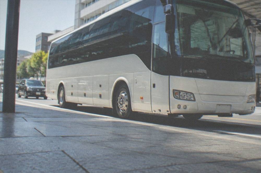 An airport limousine bus parked at a kerb beside a terminal building