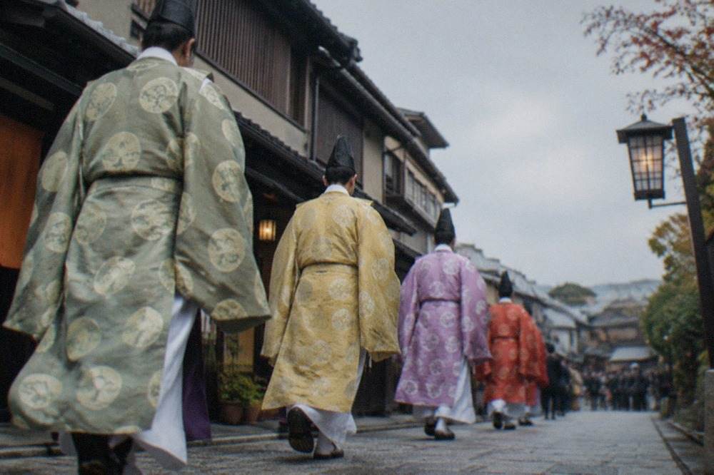 Costumed festival participants in traditional court dress walking a Kyoto street
