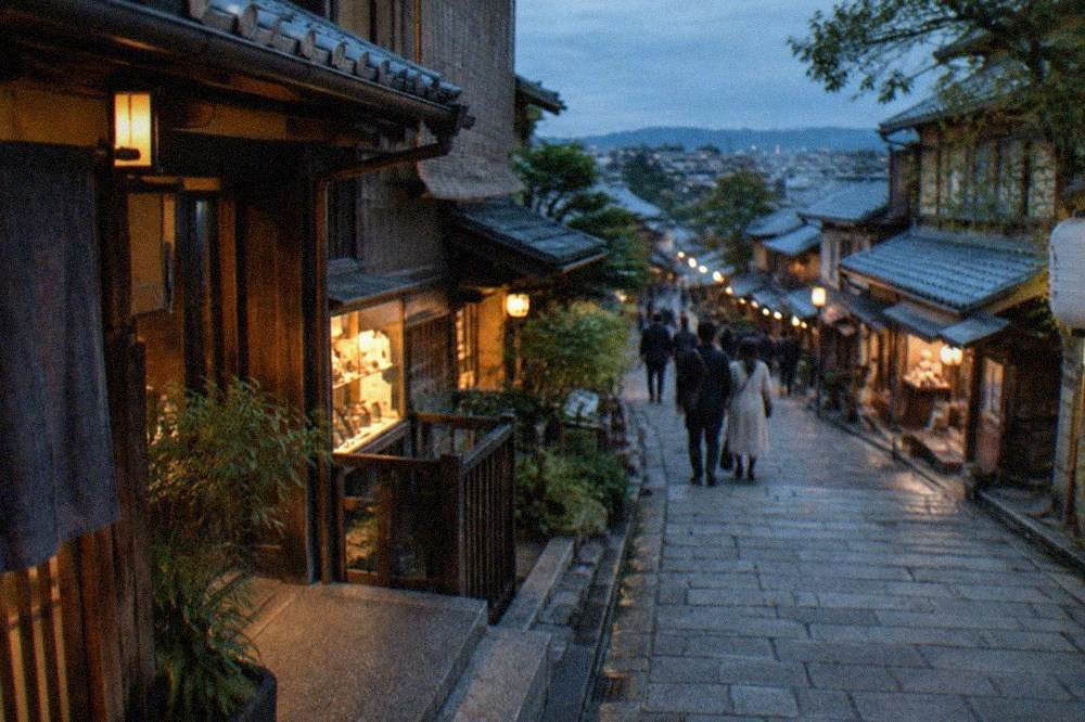 Stone-paved sloped street with traditional wooden machiya shopfronts in Higashiyama