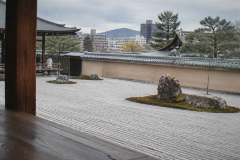 A raked gravel zen garden viewed from a wooden temple veranda in Kyoto