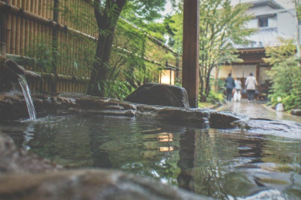 An open-air rotenburo bath at a Kyoto ryokan surrounded by bamboo and stone