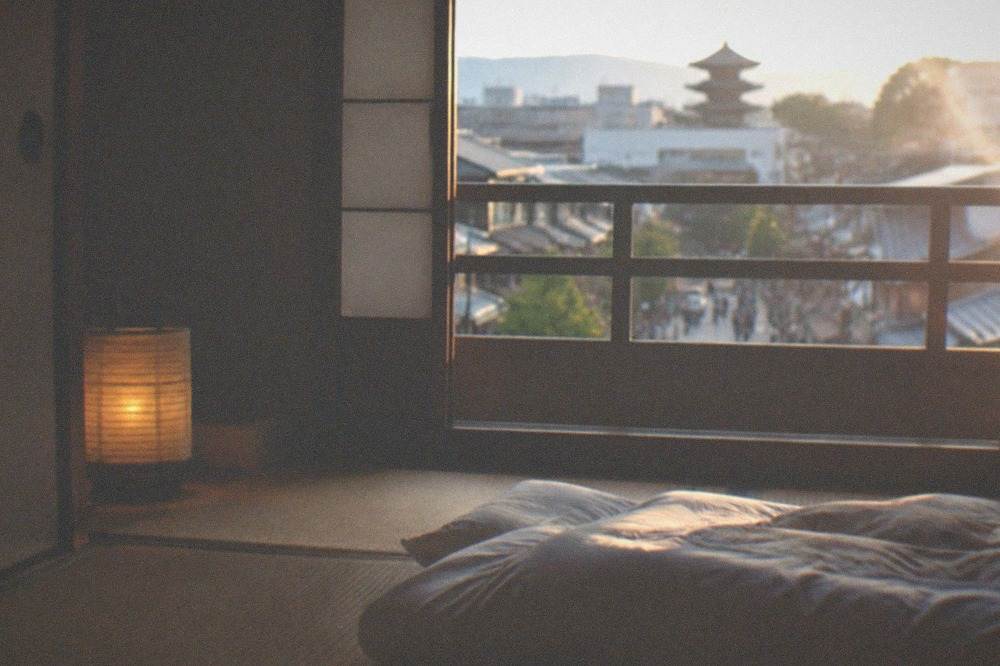 A futon laid out on tatami matting beside a paper lantern in a ryokan bedroom
