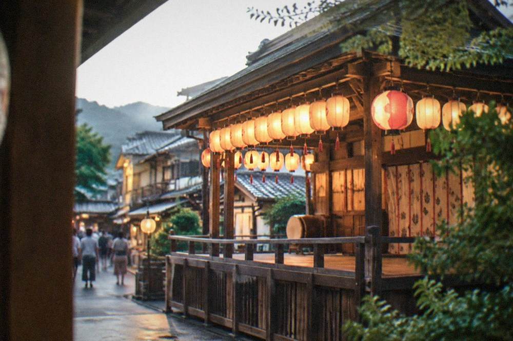 A lantern-hung wooden shrine stage glowing in the evening in Kyoto's Gion district