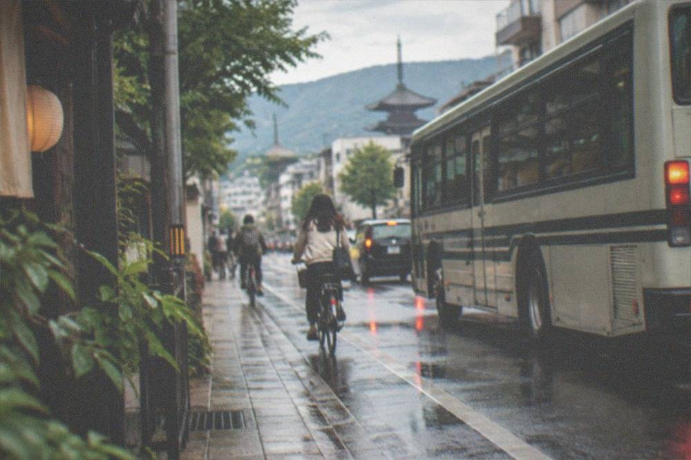 A city bus and cyclists on a narrow street in central Kyoto