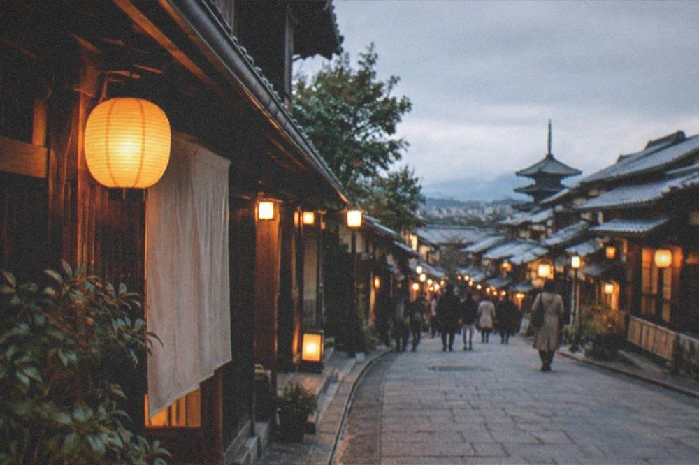 Lanterns glowing along a traditional wooden street in Gion at dusk