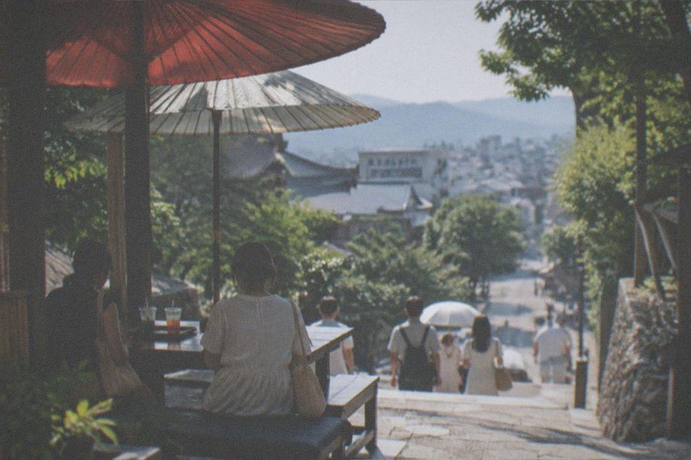 Paper umbrellas and cold drinks at a shaded Kyoto stall in summer